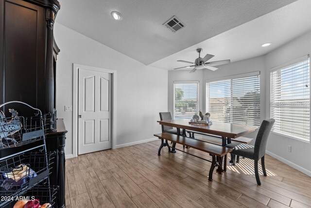 dining space with a textured ceiling, light hardwood / wood-style flooring, ceiling fan, and lofted ceiling