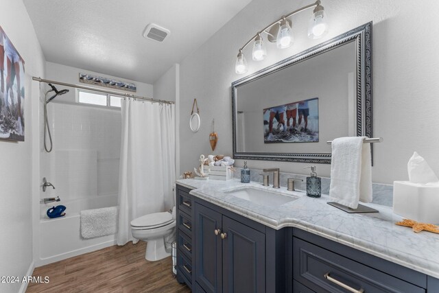 full bathroom with toilet, hardwood / wood-style floors, vanity, a textured ceiling, and shower / bath combo