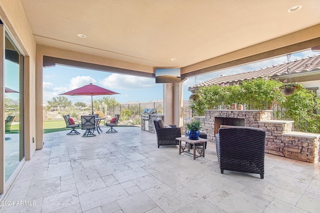 view of patio with an outdoor stone fireplace and area for grilling