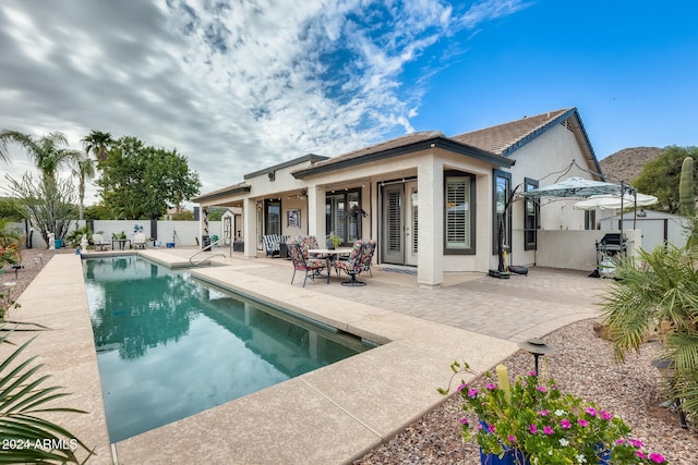 back of property featuring a fenced in pool and a patio