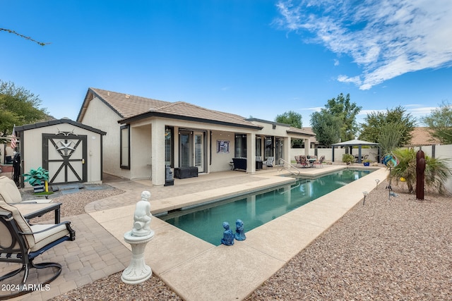 back of house with a storage shed, a fenced in pool, and a patio area