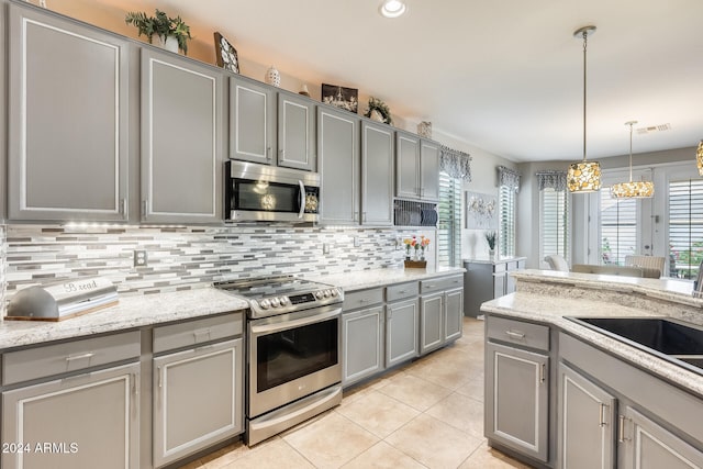 kitchen with stainless steel appliances, light tile patterned flooring, light stone counters, hanging light fixtures, and gray cabinetry