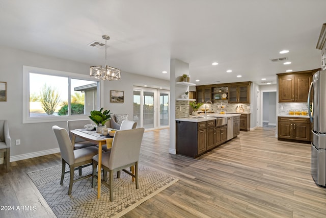 dining room with light wood-type flooring, sink, and a notable chandelier