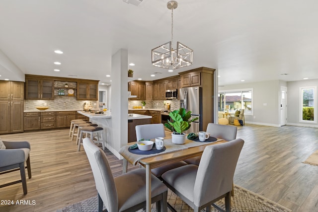 dining area with a notable chandelier and light hardwood / wood-style floors