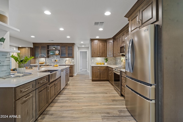 kitchen with sink, light hardwood / wood-style flooring, stainless steel appliances, decorative backsplash, and dark brown cabinetry