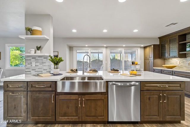 kitchen with light hardwood / wood-style floors, backsplash, dishwasher, a wealth of natural light, and sink