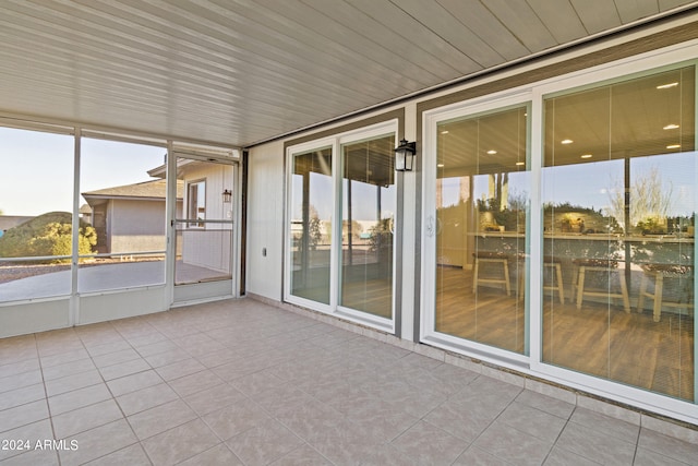 unfurnished sunroom with wood ceiling, a mountain view, and a wealth of natural light