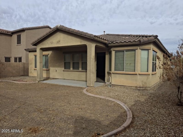 back of house with fence, stucco siding, a tile roof, and a patio area