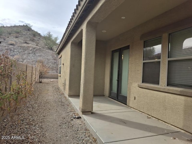 view of side of property with fence, a patio area, and stucco siding