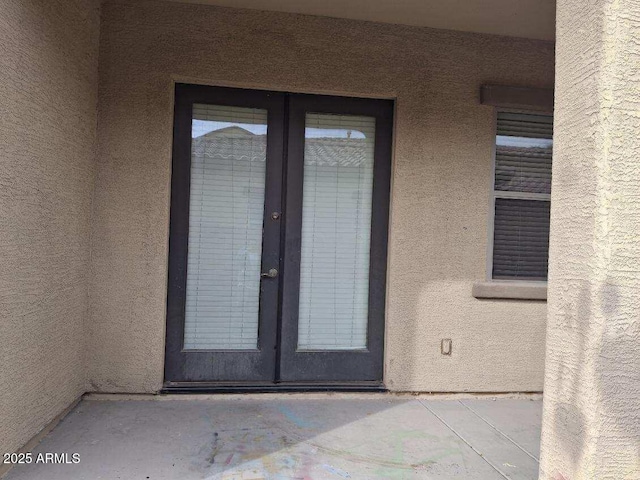 view of exterior entry featuring stucco siding and french doors