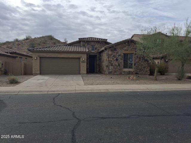 view of front facade with stucco siding, fence, a garage, a tile roof, and driveway
