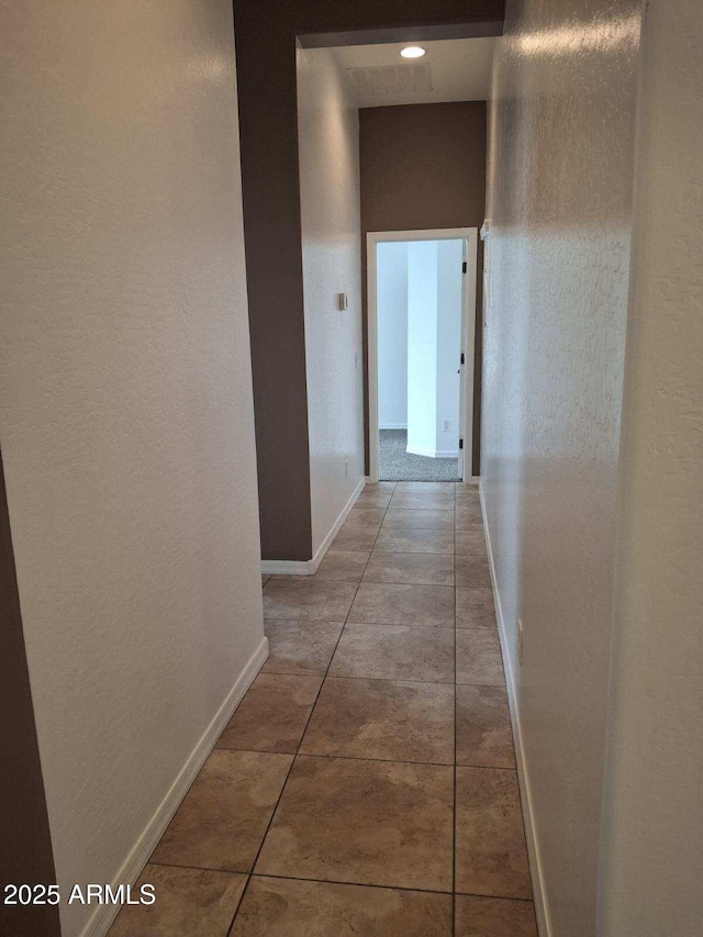 hallway featuring tile patterned floors and baseboards