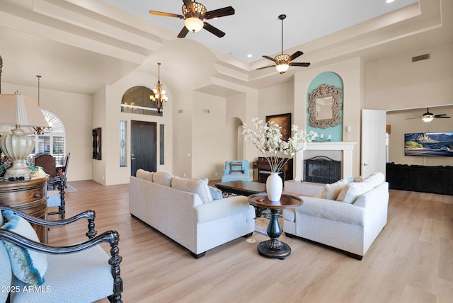 1940 N Stevens Cir, Mesa, AZ 85205 - living room with a ceiling fan, a chandelier, light wood-style flooring, a fireplace, and a towering ceiling