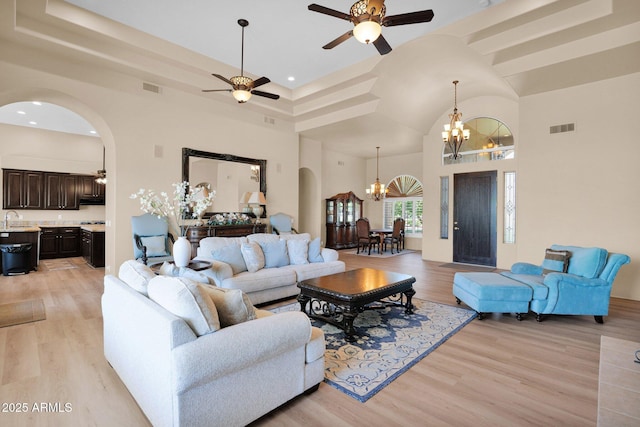 1940 N Stevens Cir, Mesa, AZ 85205 - living room with a chandelier, arched walkways, light wood-type flooring, a towering ceiling, and recessed lighting