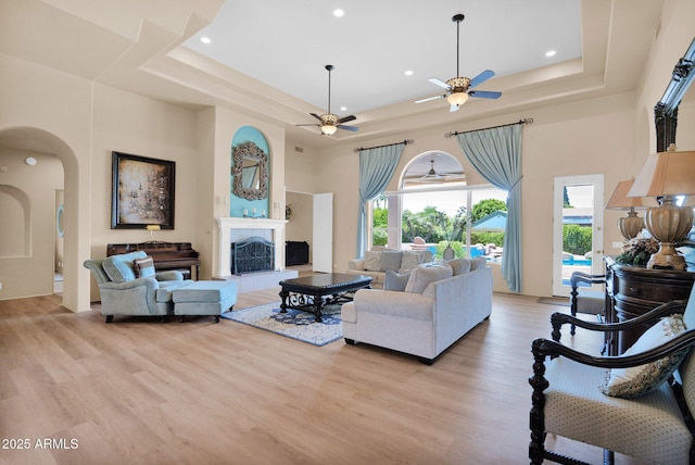1940 N Stevens Cir, Mesa, AZ 85205 - living room with a raised ceiling, arched walkways, a ceiling fan, light wood-style flooring, and a high ceiling