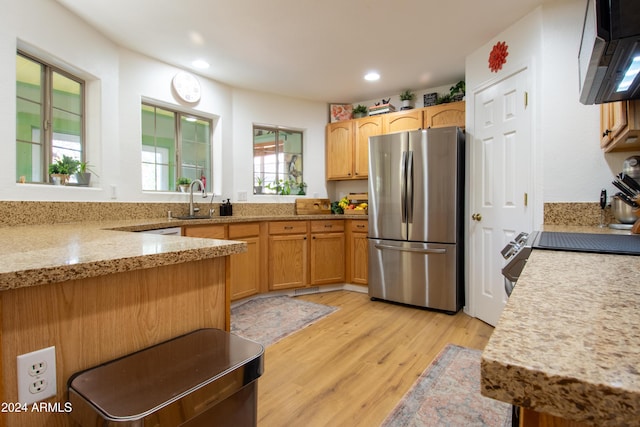 kitchen featuring stainless steel refrigerator, light stone countertops, sink, and light wood-type flooring