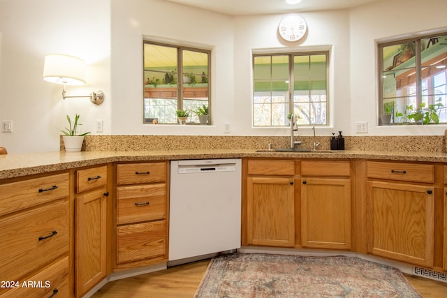 kitchen featuring dishwasher, light stone countertops, sink, and light hardwood / wood-style flooring