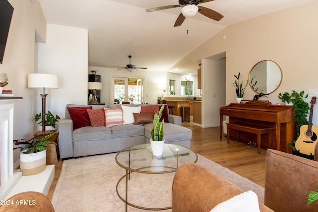 living room with ceiling fan, light hardwood / wood-style floors, and lofted ceiling