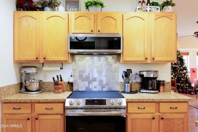 kitchen featuring appliances with stainless steel finishes, light brown cabinets, and tasteful backsplash