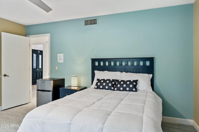 bedroom with light tile patterned floors and stainless steel refrigerator