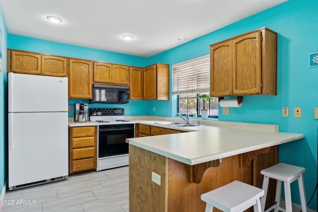 kitchen with sink, a kitchen breakfast bar, range with electric cooktop, white refrigerator, and kitchen peninsula