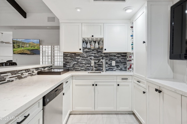 kitchen with light stone counters, white cabinets, tasteful backsplash, and dishwasher