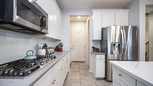 kitchen with white cabinets, decorative backsplash, light stone countertops, and appliances with stainless steel finishes