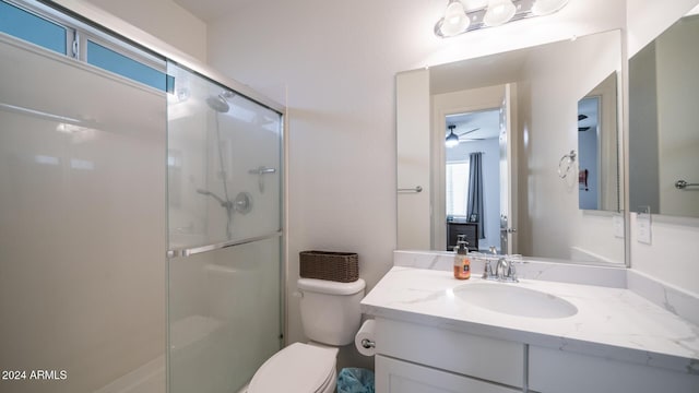 bathroom featuring ceiling fan, vanity, a shower with shower door, and toilet