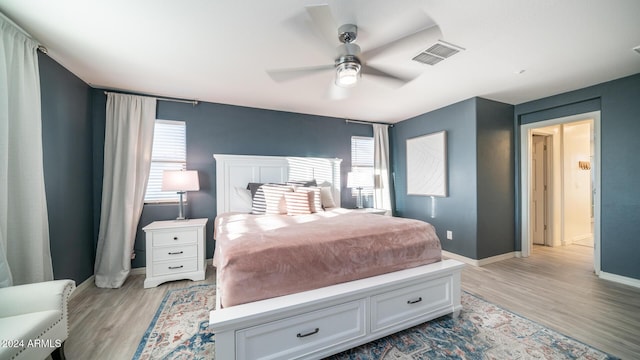 bedroom with ceiling fan, light hardwood / wood-style floors, and multiple windows