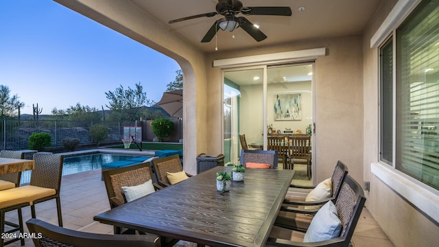 patio terrace at dusk featuring a fenced in pool and ceiling fan