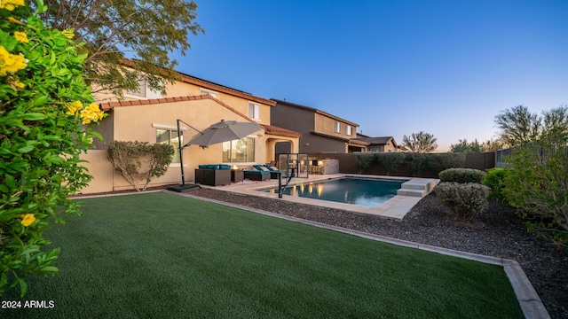 pool at dusk featuring a lawn, an outdoor living space, and a patio