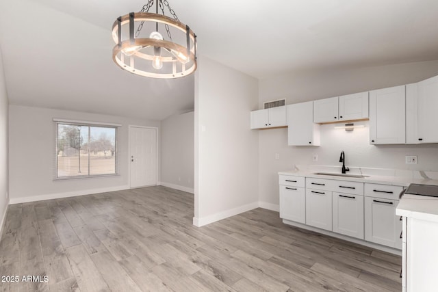 kitchen featuring a chandelier, a sink, visible vents, vaulted ceiling, and light countertops