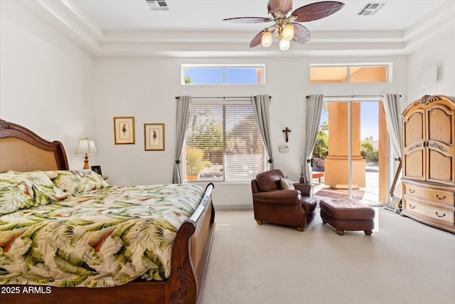 bedroom with ceiling fan, access to exterior, and a raised ceiling