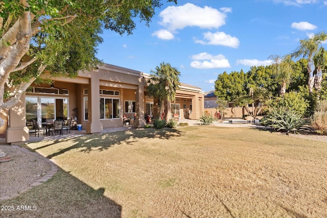 rear view of property with a patio and a lawn