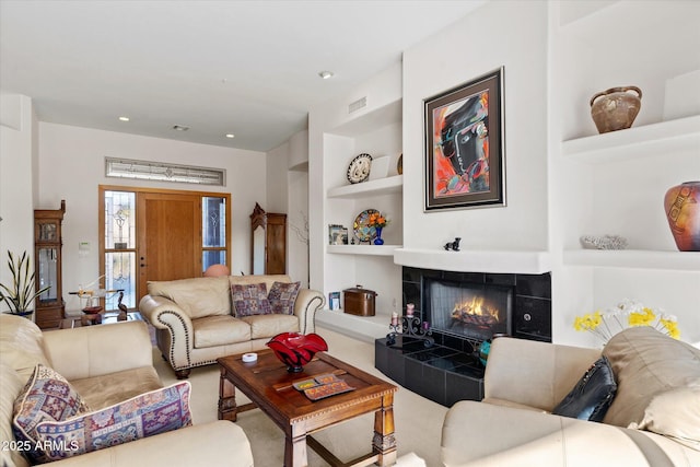 living room featuring a tile fireplace and built in shelves