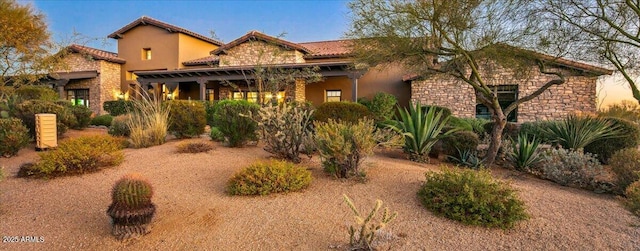 view of front of home featuring stone siding, stucco siding, and a tile roof