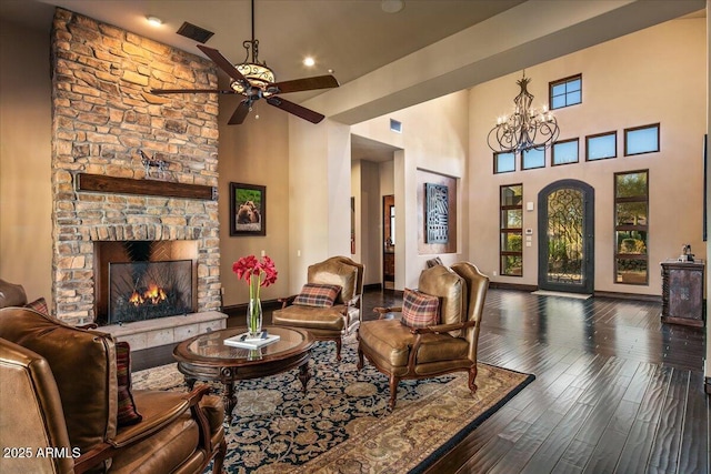 living area featuring wood finished floors, plenty of natural light, ceiling fan with notable chandelier, and visible vents