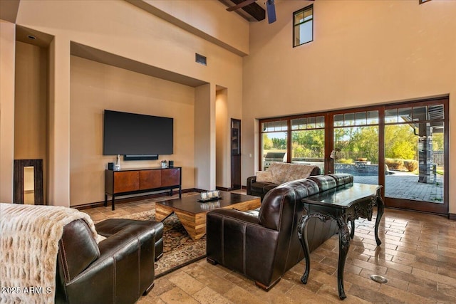 living area with visible vents, baseboards, and a high ceiling