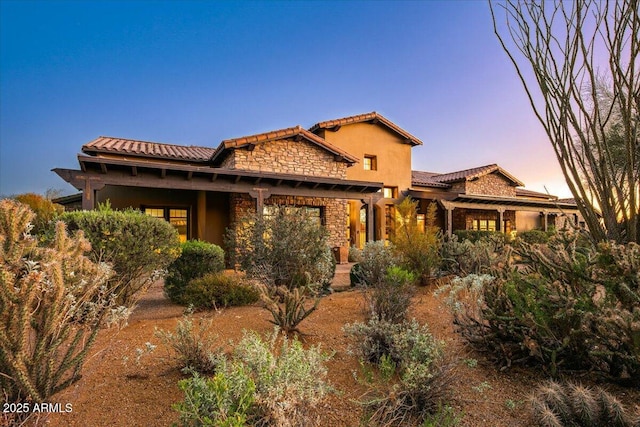 mediterranean / spanish house with a tiled roof, stone siding, and stucco siding