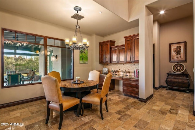 dining space featuring a notable chandelier, baseboards, and stone finish flooring