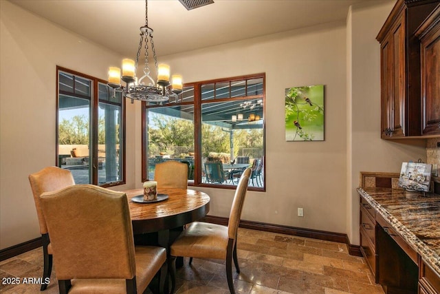 dining space featuring a notable chandelier, baseboards, and stone tile flooring