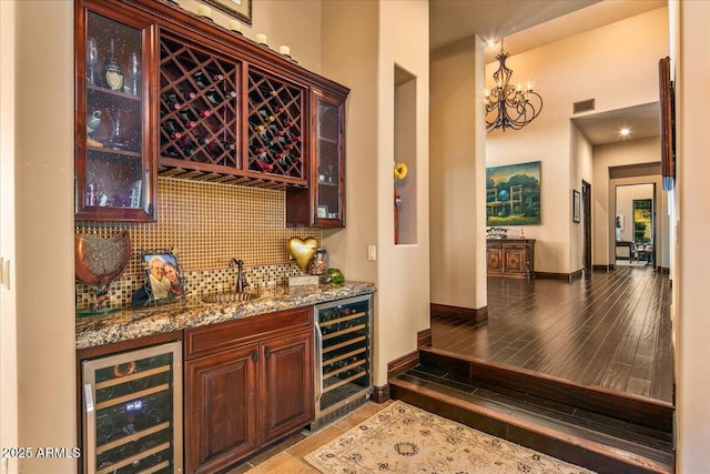 bar featuring indoor wet bar, beverage cooler, visible vents, and backsplash