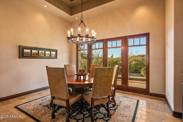 dining area with baseboards, recessed lighting, stone tile flooring, a towering ceiling, and a notable chandelier