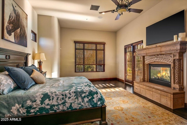 bedroom featuring visible vents, baseboards, wood finished floors, and a fireplace