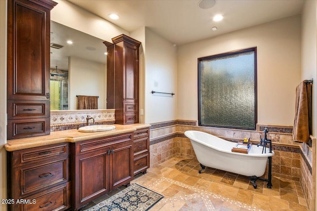 bathroom featuring vanity, a wainscoted wall, a freestanding tub, recessed lighting, and tile walls