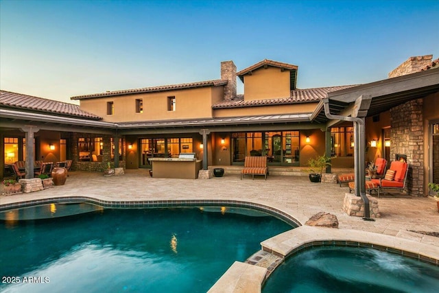 back of house with a patio area, area for grilling, a pool with connected hot tub, and outdoor dry bar