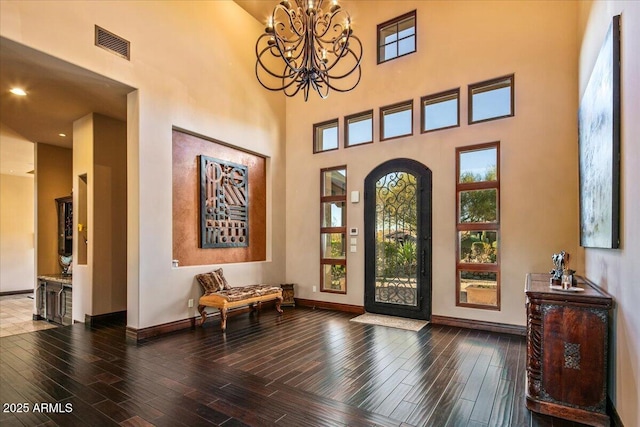 entryway with a chandelier, visible vents, baseboards, and wood finished floors