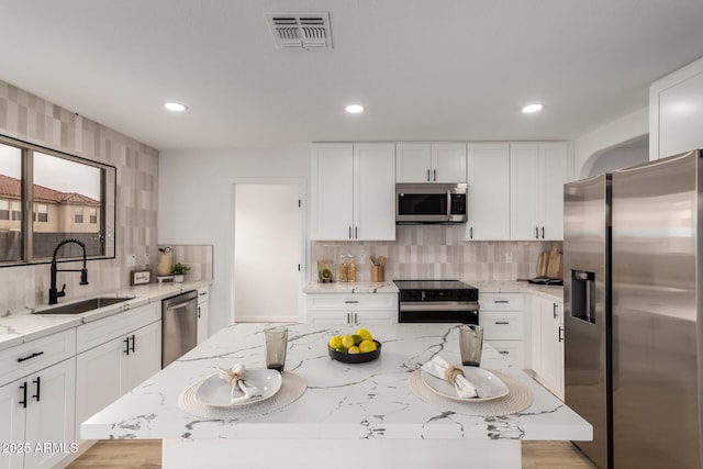 10625 E Bramble Ave, Mesa, AZ 85208 - kitchen featuring appliances with stainless steel finishes, a sink, tasteful backsplash, light stone countertops, and white cabinetry