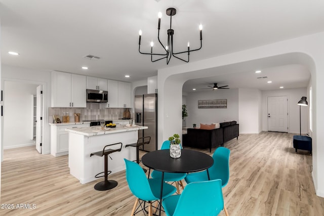 10625 E Bramble Ave, Mesa, AZ 85208 - dining space with arched walkways, light wood-style flooring, recessed lighting, a chandelier, and a ceiling fan