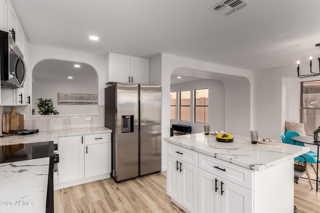 10625 E Bramble Ave, Mesa, AZ 85208 - kitchen featuring appliances with stainless steel finishes, arched walkways, light wood-style floors, white cabinetry, and light stone countertops